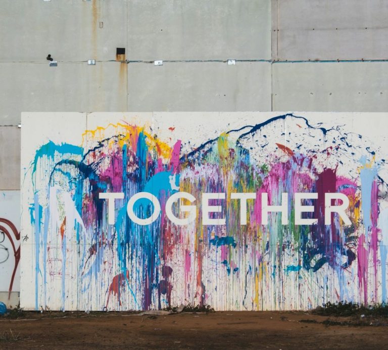 Bunte Wandmalerei mit dem Wort "TOGETHER" in großen Buchstaben.